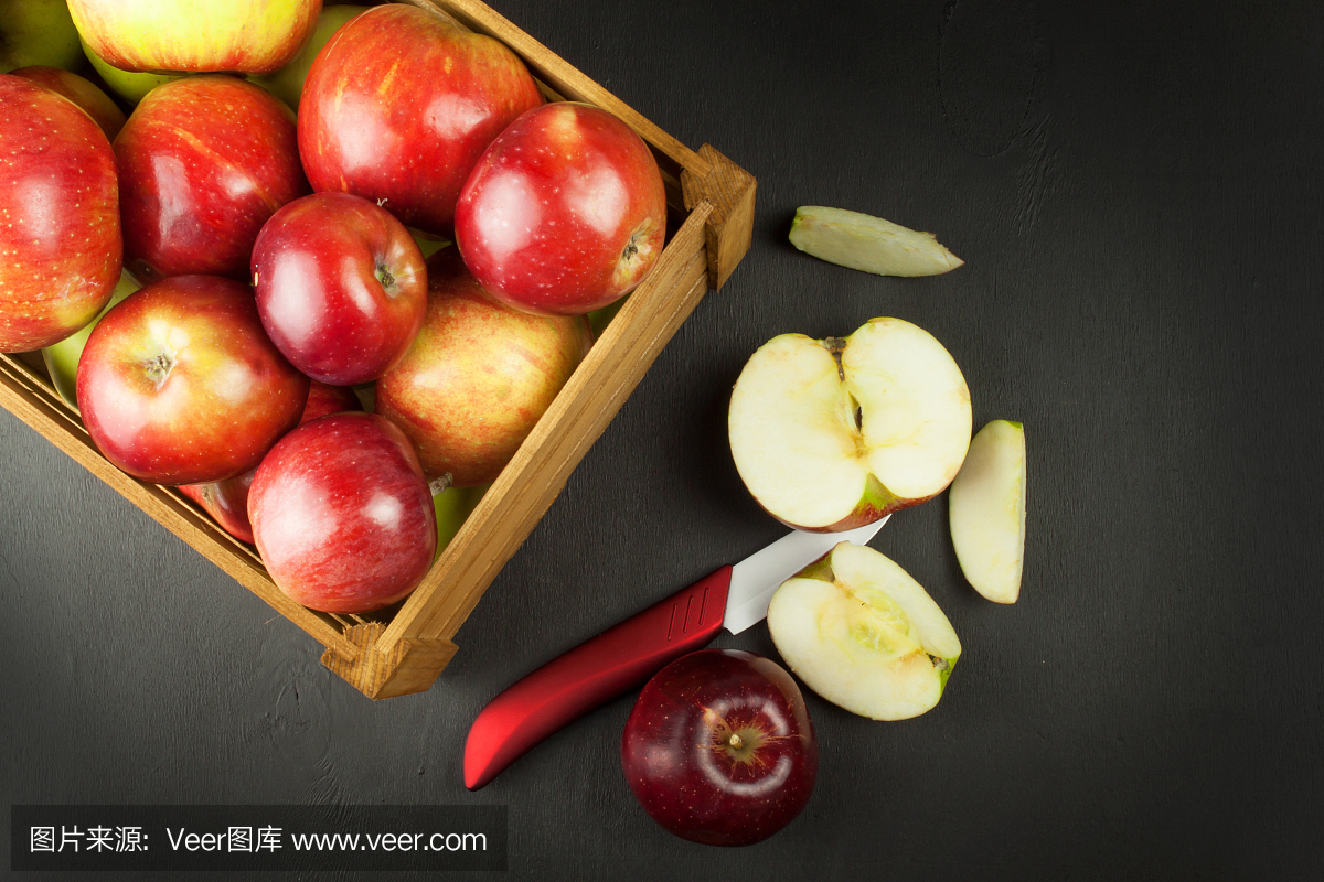 陶瓷刀的水果。新鲜的红色秋天苹果装在木箱里